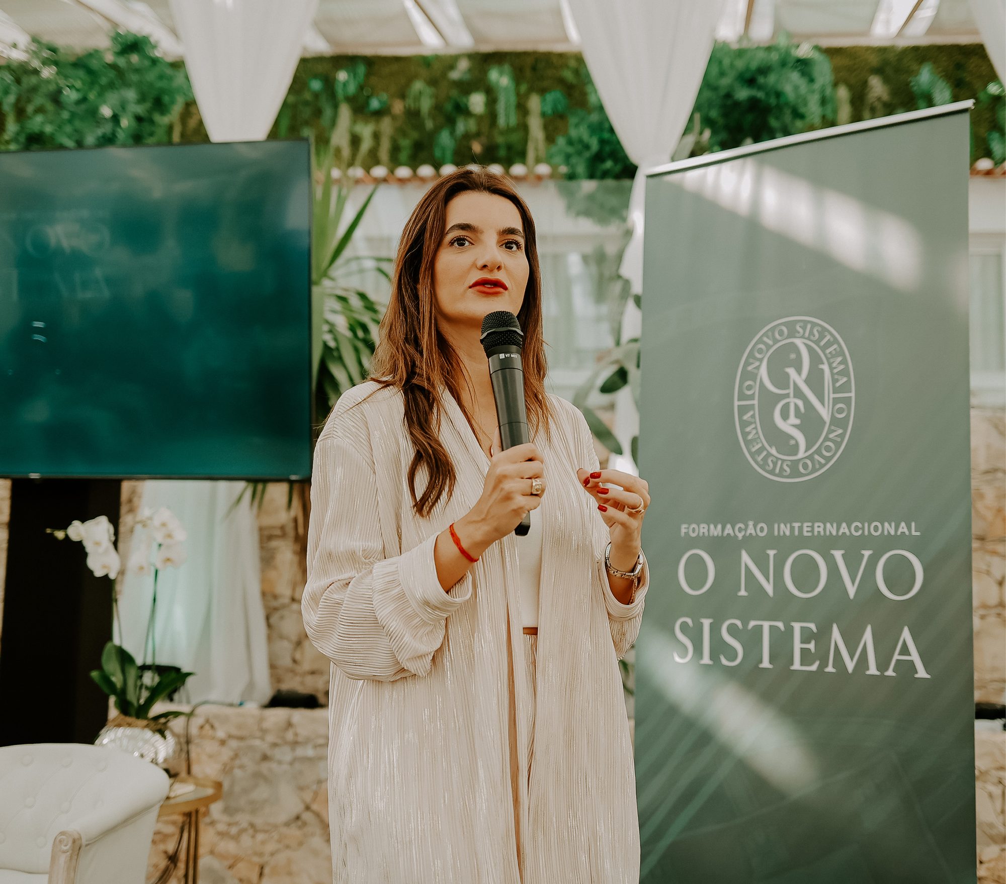 Ana Lisboa falando ao microfone durante evento do Instituto ALTIS Lisboa